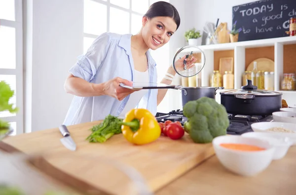 Junge Frau steht am Herd in der Küche — Stockfoto