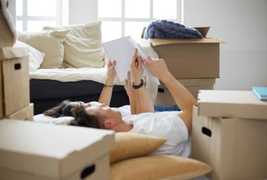 Yeni evlerinde karton kutuları açıp yere uzanan ve bir aile albümüne bakan sevimli çift.