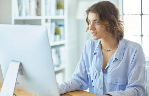 Csinos fiatal nő ül az asztalnál, és gépel a laptopon — Stock Fotó