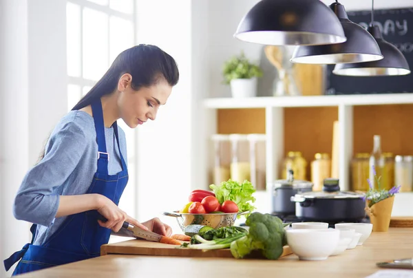 Jovem mulher cortando legumes na cozinha em casa — Fotografia de Stock