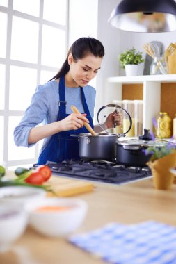 Mutfakta ahşap kaşıkla yemek pişiren kadın