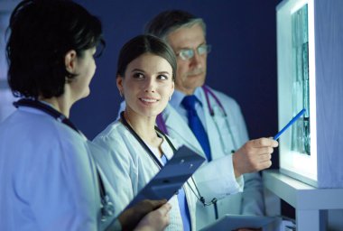 Bir grup doktor bir klinikte röntgenleri inceliyor, teşhis koymayı düşünüyorlar.
