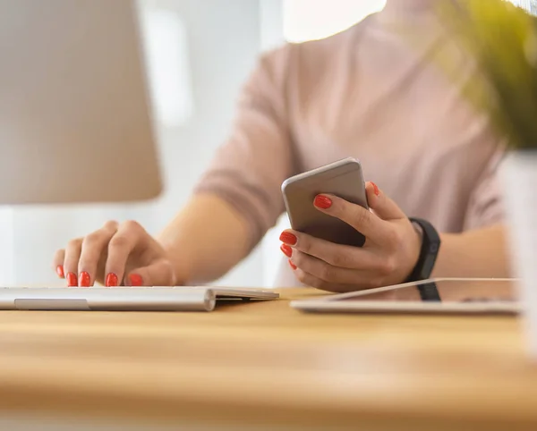 Mulher feliz trabalhando usando vários dispositivos em uma mesa em casa — Fotografia de Stock