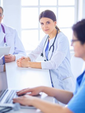 Ciddi bir tıbbi ekip hastaları parlak bir ofiste tartışıyor.