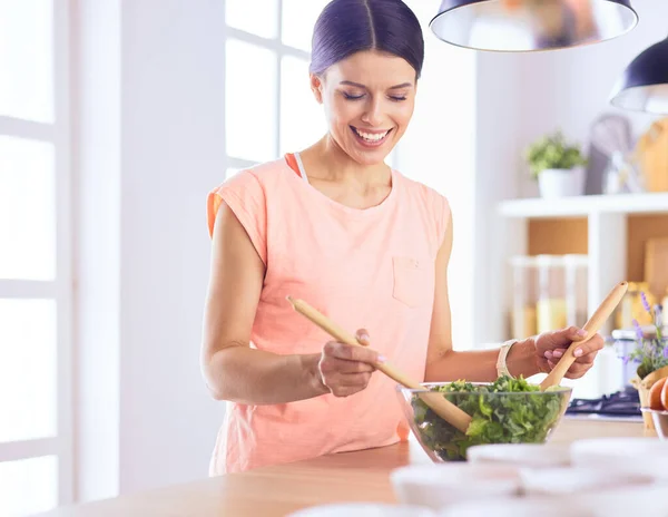 Smiling young woman mixing fresh salad in the kitchen. — Stock Photo, Image