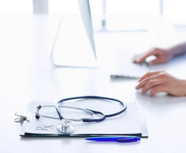 Kadın doktor masada oturuyor ve hastanede dizüstü bilgisayarla çalışıyor.