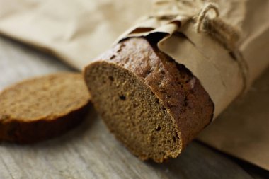 Dilimlenmiş ekmek somunu tahtadan masanın üzerinde kağıda sarılmış.