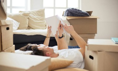 Yeni evlerinde karton kutuları açıp yere uzanan ve bir aile albümüne bakan sevimli çift.