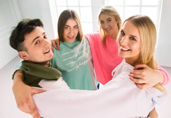 Heureux amis souriants, groupe de jeunes debout et embrassant ensemble — Photo