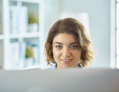 Evdeki bir masada birden fazla cihaz kullanarak çalışan mutlu kadın.