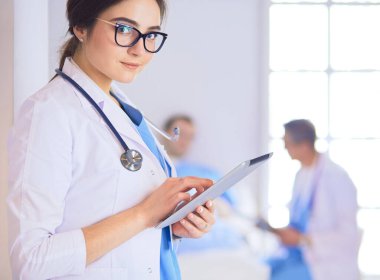 Hastane lobisinde tablet bilgisayar kullanan kadın doktor.