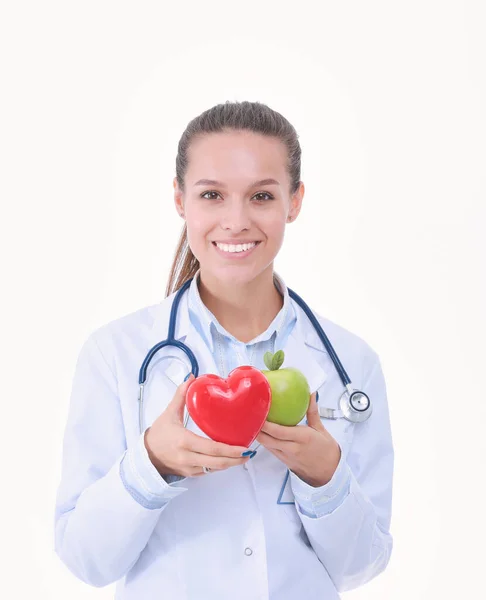 Bela médica sorridente segurando coração vermelho e maçã verde. Mulher médica — Fotografia de Stock