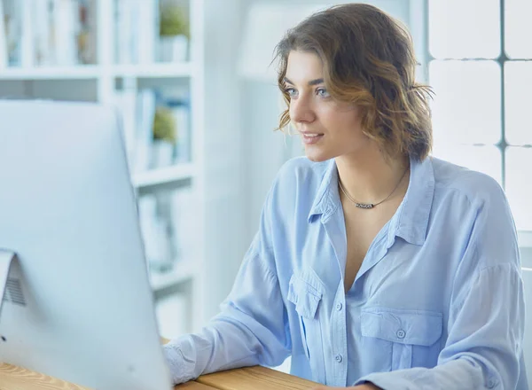 Bella giovane donna seduta alla scrivania e digitando sul computer portatile — Foto Stock