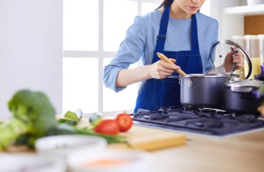 Mutfakta ahşap kaşıkla yemek pişiren kadın