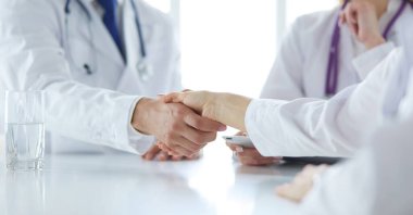 Doktor ofiste erkek bir hastayla el sıkışıyor.