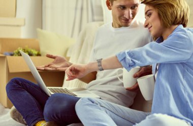 Çift birlikte kanepeye taşınıyor. Laptop tableti ve kutularla koltukta dinleniyorlar.