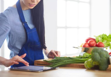 Mutfakta sebze doğrayan genç bir kadın.