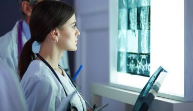 Bir grup doktor bir klinikte röntgenleri inceliyor, teşhis koymayı düşünüyorlar.