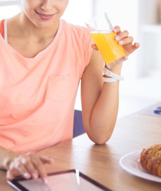 Mutfakta dijital tablet kullanan güzel genç bir kadın.