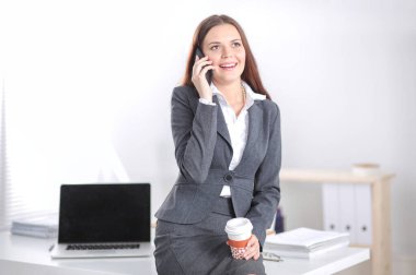 Modern ofiste telefonla konuşan başarılı, güzel bir kadın. Güzel, başarılı bir kadın.