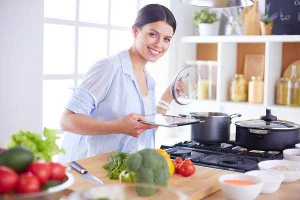 Giovane donna in piedi vicino al fornello in cucina — Foto Stock