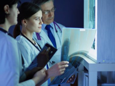 Bir grup doktor bir klinikte röntgenleri inceliyor, teşhis koymayı düşünüyorlar.