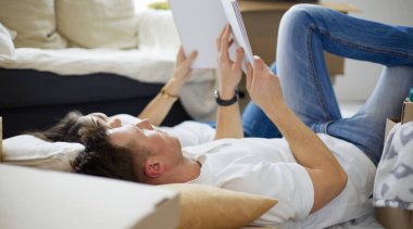 Yeni evlerinde karton kutuları açıp yere uzanan ve bir aile albümüne bakan sevimli çift.