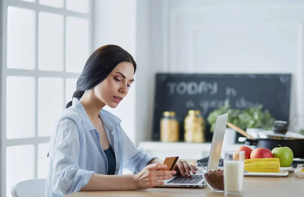 Donna sorridente shopping online con computer e carta di credito in cucina — Foto Stock