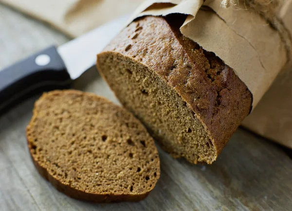 Ein in Papier verpackter Laib Brot auf einem Holztisch — Stockfoto