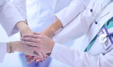 Doktorlar ve hemşireler tıbbi bir ekipte el ele tutuşuyorlar.