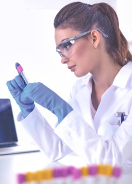 Kadın araştırmacı, beyaz arka planda izole edilmiş ilaç şişeleri ve mataralarla çevrili.