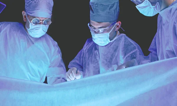 在手术室工作的一组外科医生用蓝色调.执行业务的医疗小组 — 图库照片