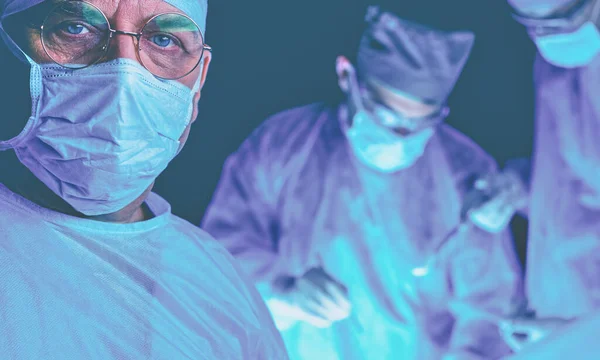Groupe de chirurgiens au travail en salle d'opération tonique en bleu. Équipe médicale effectuant l'opération — Photo