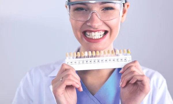 Dentiste féminine attrayante avec des outils, debout sur fond gay — Photo