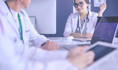 Ciddi bir tıbbi ekip parlak bir ofiste dizüstü bilgisayar kullanıyor.