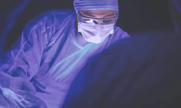 Läkare som utför operation i en mörk bakgrund. — Stockfoto