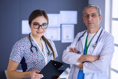 Bir doktor ekibi, kadın ve erkek, ofiste bekliyorlar.