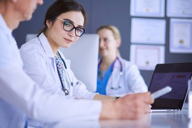 Ciddi bir tıbbi ekip parlak bir ofiste dizüstü bilgisayar kullanıyor.