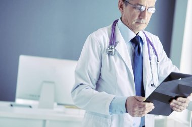 Erkek doktor hastanedeki panoya notlar yazıyor.