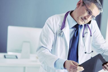 Erkek doktor hastanedeki panoya notlar yazıyor.