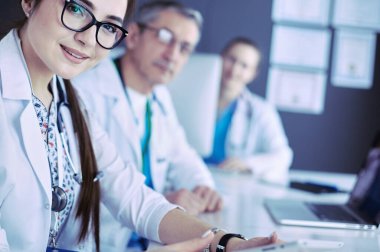 Ciddi bir tıbbi ekip parlak bir ofiste dizüstü bilgisayar kullanıyor.