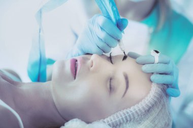 Kaşlar için kalıcı makyaj. Güzellik salonunda kalın kaşlı güzel bir kadın.