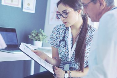 Parlak bir ofiste konuşan iki doktor.