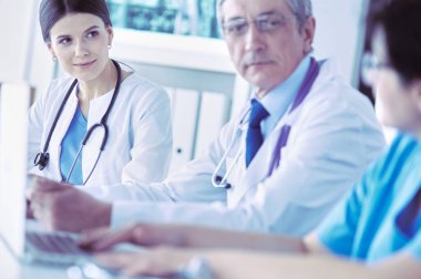 Parlak bir hastane odasında meslektaşlarıyla çalışan gülümseyen bir doktor.