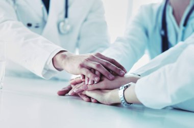 Doktorlar el ele tutuşup yakın çekim yapıyor.