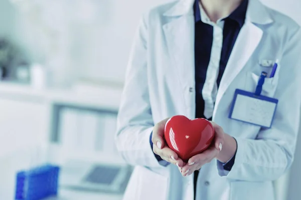 Un médecin avec stéthoscope examinant le cœur rouge, isolé sur fond blanc — Photo