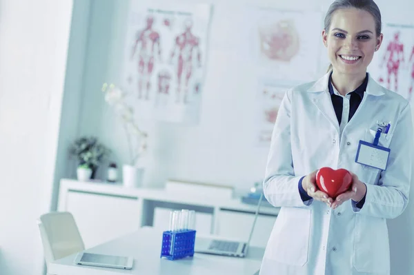 Een arts met stethoscoop onderzoek rode hart, geïsoleerd op witte achtergrond — Stockfoto