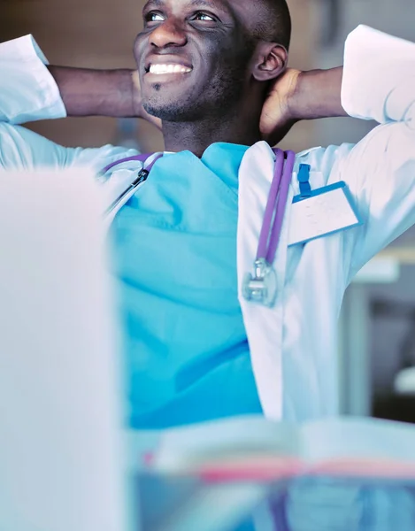 Mladý africký lékař pracující na notebooku na stole — Stock fotografie