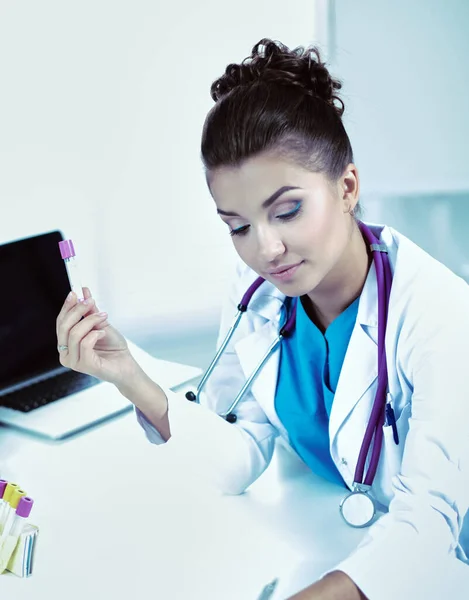 Retrato de assistente de laboratório muito feminino analisando uma amostra de sangue no hospital perto do laptop — Fotografia de Stock