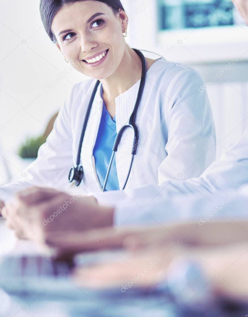 Smiling doctor using a laptop working with her colleagues in a bright hospital room